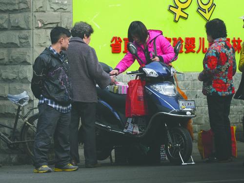 双华路菜市场门口，红衣女子正在收购附近居民送来的药品